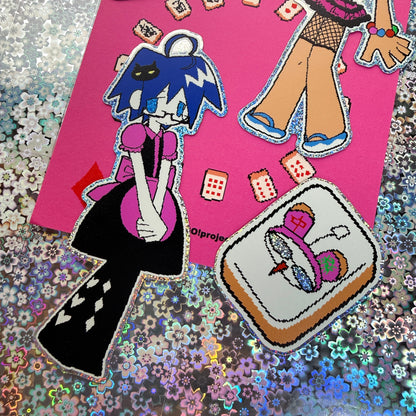 A close-up of a sticker on a pink backing sheet, surrounded by a glittery multicolor background. The sticker feature anime-style characters and objects, including a character with blue hair and a black dress, and a patch of a pink and purple hat on a brown background.